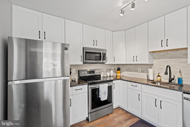 11200 Rienzi Pl Unit 201, Manassas, VA 20109 - kitchen featuring dark stone countertops, a sink, light wood-type flooring, white cabinets, and appliances with stainless steel finishes