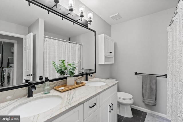 11200 Rienzi Pl Unit 201, Manassas, VA 20109 - bathroom featuring washing machine and clothes dryer, tile patterned floors, a sink, and toilet