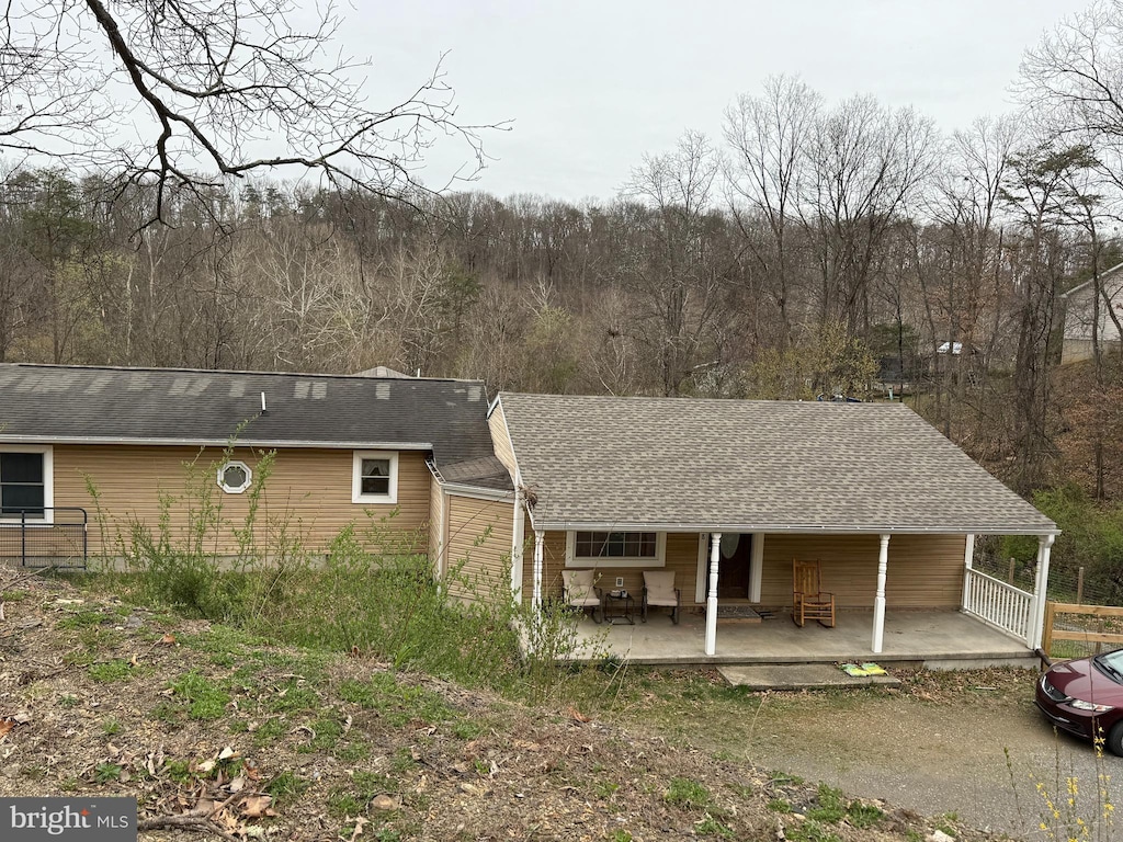 back of property with covered porch and a shingled roof