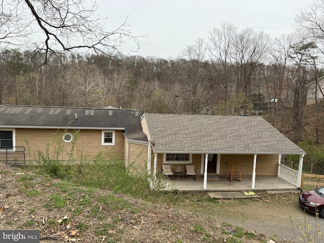 back of property with covered porch and a shingled roof