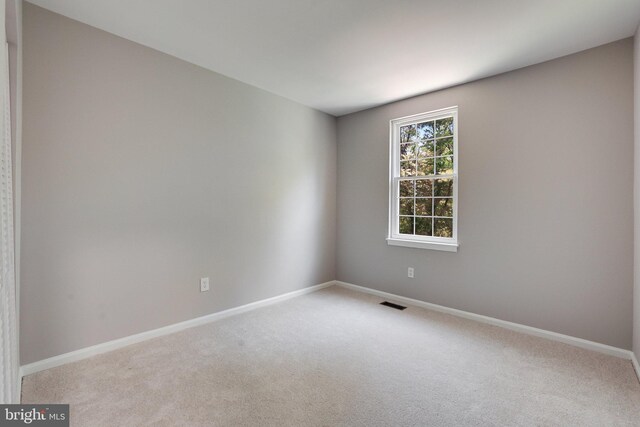 carpeted empty room featuring baseboards and visible vents