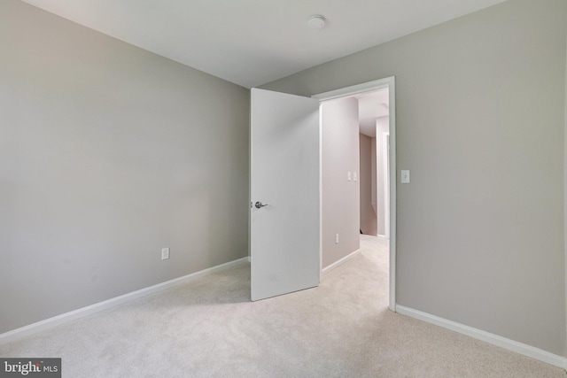 empty room featuring light colored carpet and baseboards
