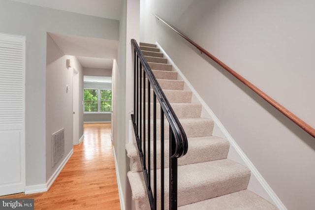 staircase with visible vents, baseboards, and wood finished floors