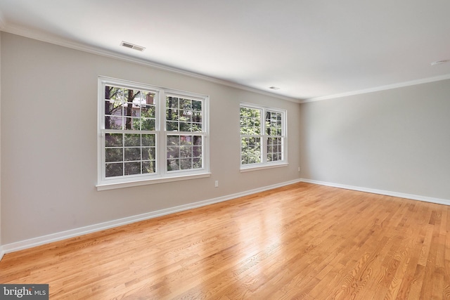 spare room featuring crown molding, baseboards, wood finished floors, and visible vents