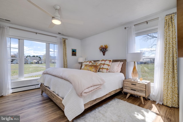 901 Riverside Ave, Grottoes, VA 24441 - bedroom with visible vents, a ceiling fan, a baseboard heating unit, and wood finished floors