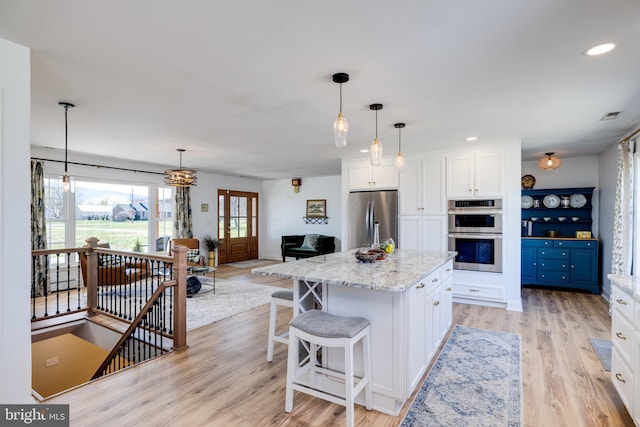 901 Riverside Ave, Grottoes, VA 24441 - kitchen with light wood-style flooring, a center island, white cabinetry, light stone countertops, and stainless steel appliances