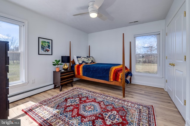 901 Riverside Ave, Grottoes, VA 24441 - bedroom featuring visible vents, multiple windows, a baseboard heating unit, and light wood finished floors