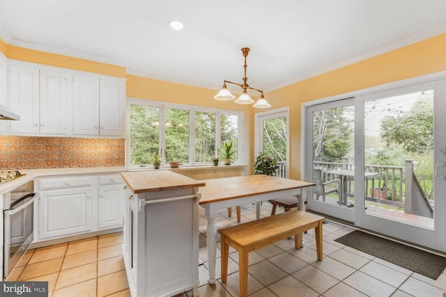 2709 Mckinley St NW, Washington, DC 20015 - kitchen with wood counters, light tile patterned floors, white cabinets, stainless steel oven, and hanging light fixtures