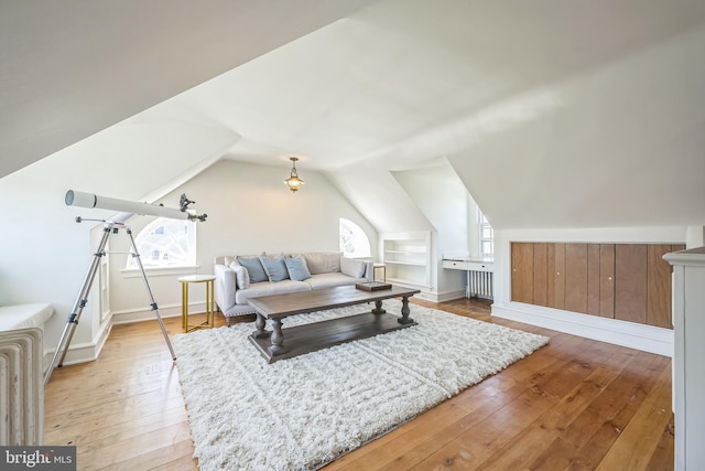 additional living space with light wood finished floors, baseboards, and vaulted ceiling