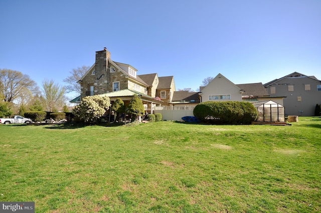 view of yard featuring an outbuilding, fence, and a greenhouse