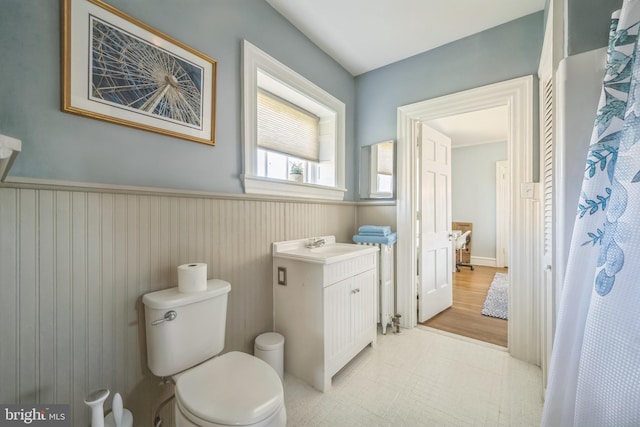 bathroom featuring toilet, vanity, and a wainscoted wall