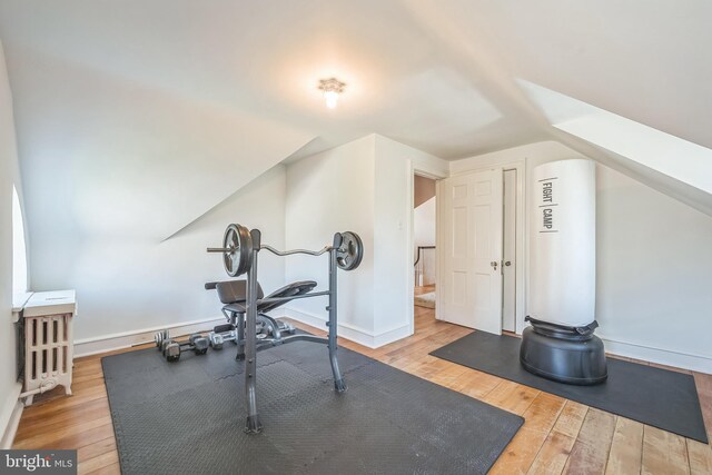 exercise room featuring baseboards, hardwood / wood-style floors, and lofted ceiling