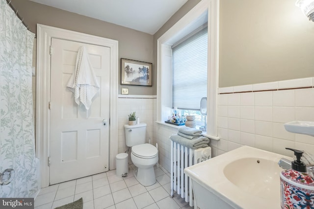 bathroom featuring tile patterned floors, tile walls, radiator, and a wealth of natural light