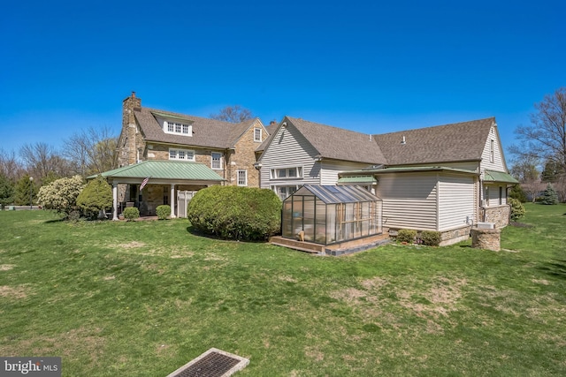 rear view of house featuring an outdoor structure, a chimney, an exterior structure, a yard, and a shingled roof