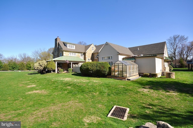back of property featuring an exterior structure, a yard, a chimney, and an outbuilding