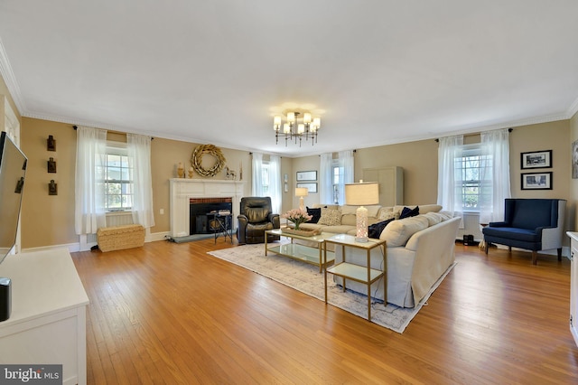 living room featuring a chandelier, crown molding, plenty of natural light, and light wood-style floors