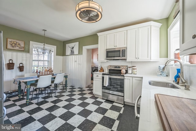 kitchen featuring stainless steel appliances, white cabinets, light countertops, and a sink