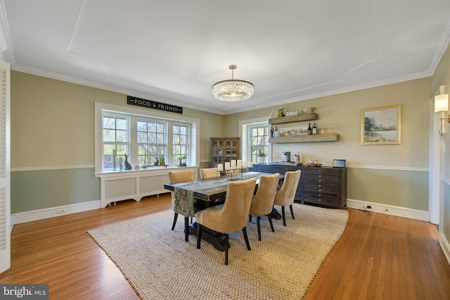 dining space featuring crown molding, wood finished floors, a notable chandelier, and baseboards