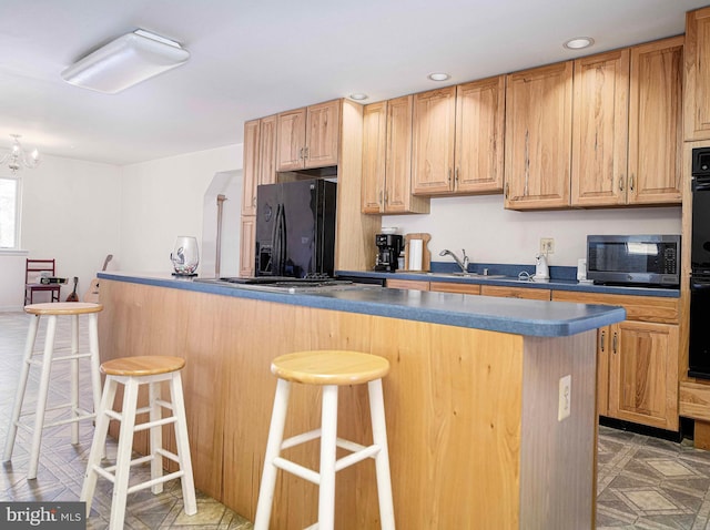 kitchen with black fridge with ice dispenser, a sink, a breakfast bar area, and dark countertops
