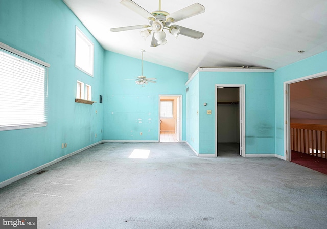 unfurnished bedroom featuring carpet flooring, vaulted ceiling, baseboards, a closet, and a walk in closet