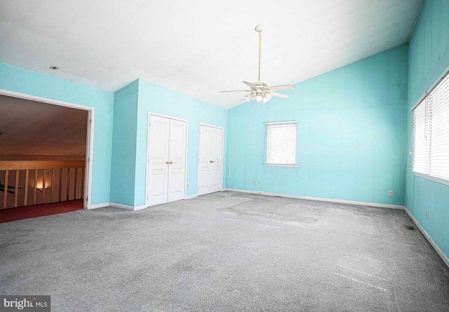 carpeted spare room featuring vaulted ceiling, a ceiling fan, and baseboards