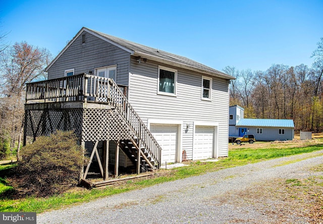 rear view of house with an attached garage, stairway, a wooden deck, and driveway
