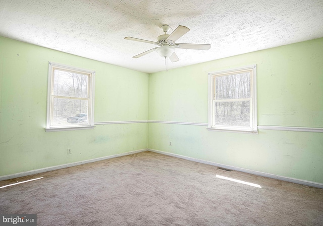 spare room featuring a ceiling fan, visible vents, carpet floors, and a textured ceiling