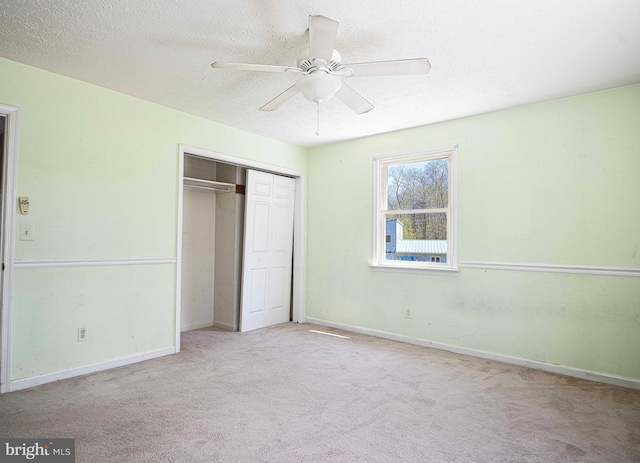 unfurnished bedroom featuring a textured ceiling, baseboards, carpet floors, and a closet