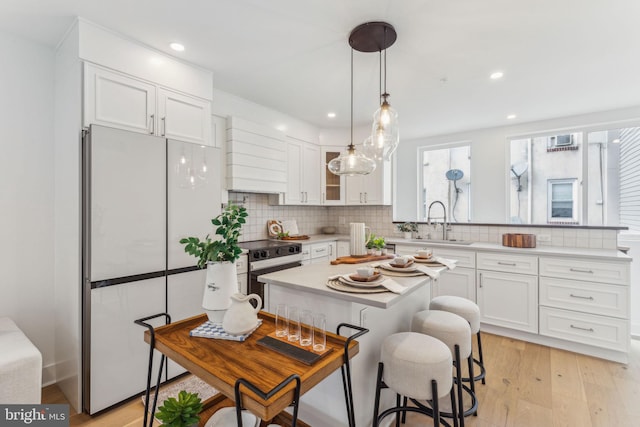 kitchen with a sink, white cabinets, freestanding refrigerator, and decorative backsplash