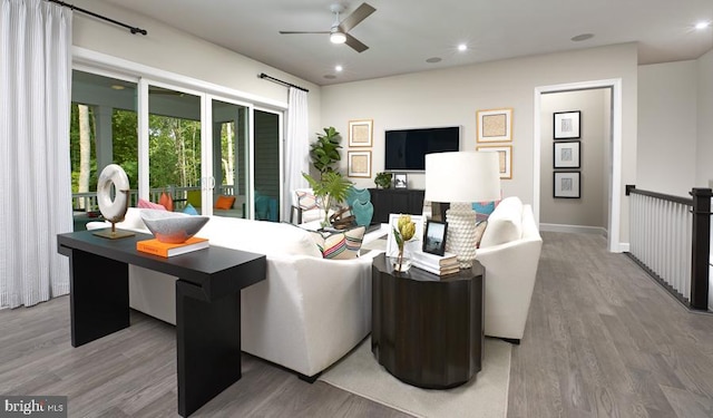 living area featuring wood finished floors, baseboards, and a ceiling fan
