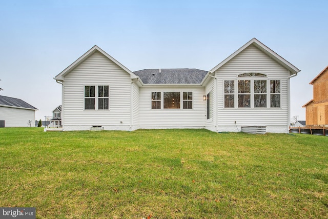 rear view of house with a yard and a shingled roof