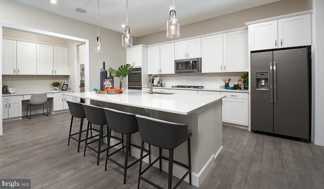 kitchen with a sink, a breakfast bar, dark wood-style flooring, and stainless steel appliances
