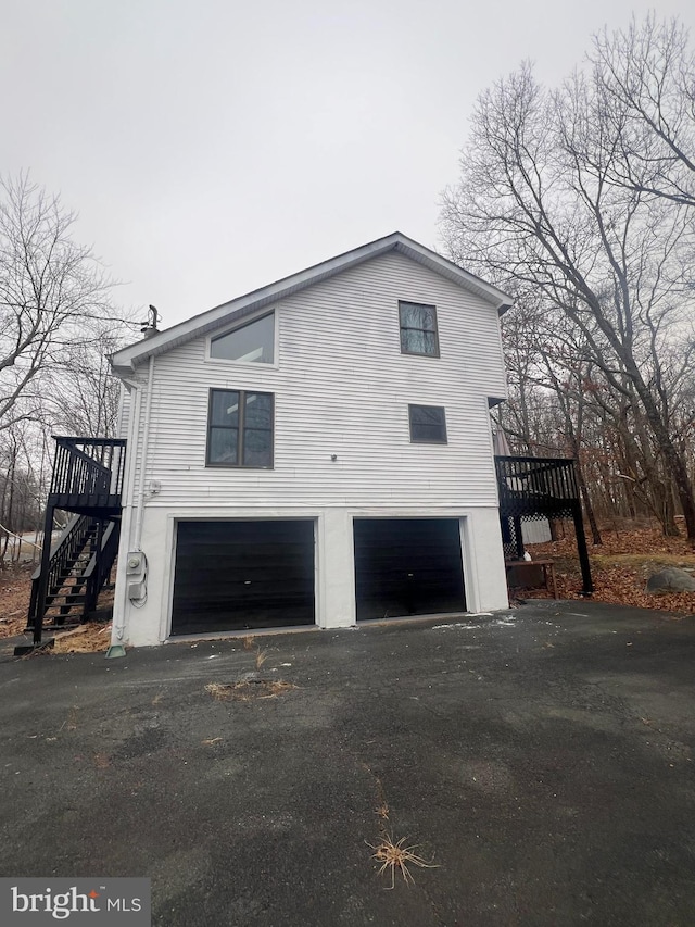 1076 Lancaster Dr, Bushkill, PA 18324 - view of home's exterior with a garage, aphalt driveway, stairway, and a wooden deck