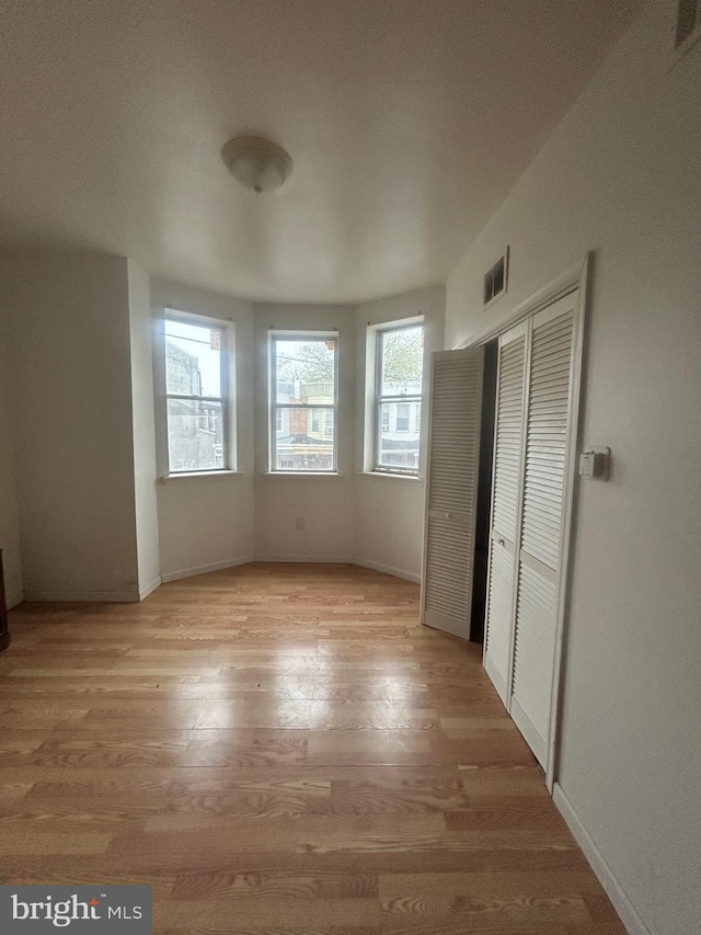unfurnished bedroom with a closet, visible vents, baseboards, and light wood-style flooring