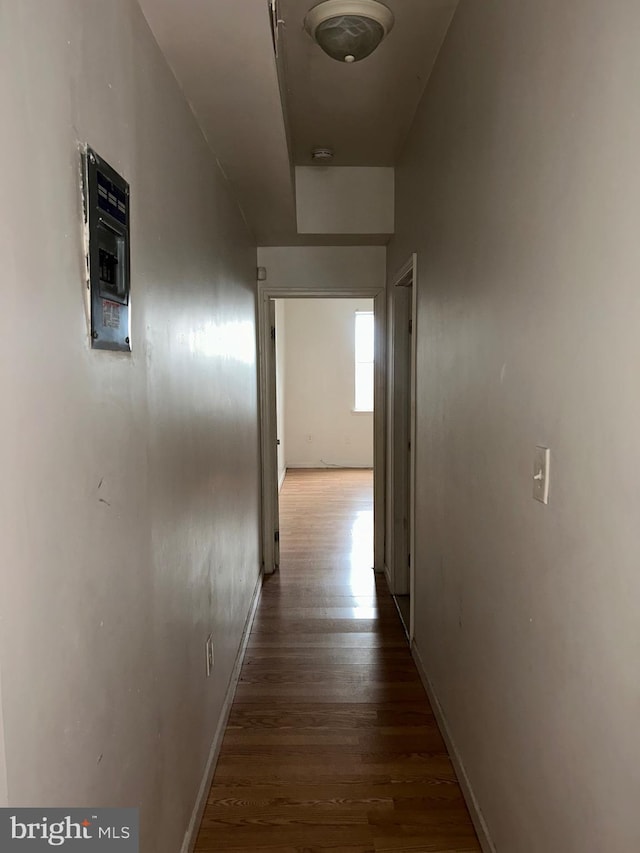 corridor featuring baseboards and wood finished floors