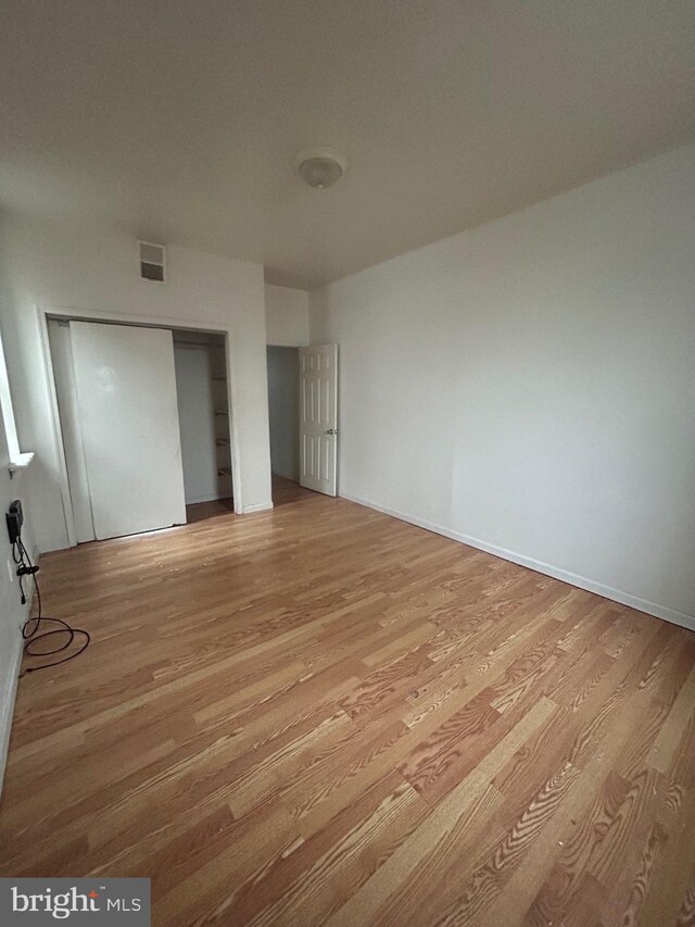 unfurnished bedroom with a closet, light wood finished floors, and visible vents