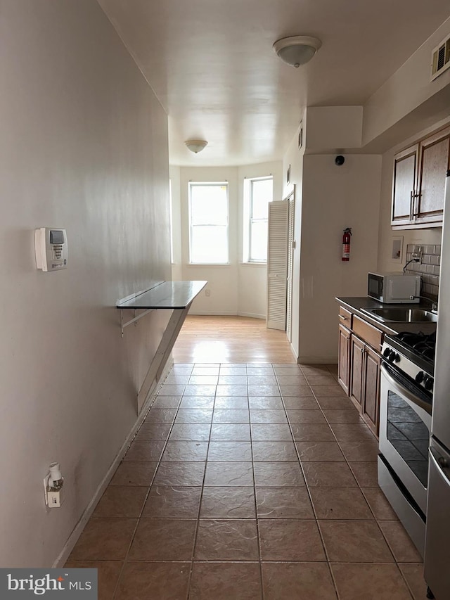kitchen with tile patterned floors, visible vents, stainless steel range with gas stovetop, and baseboards