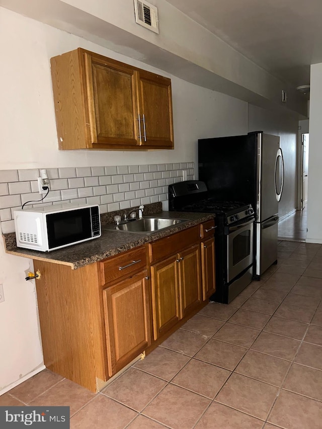 kitchen with stainless steel gas stove, white microwave, visible vents, a sink, and backsplash