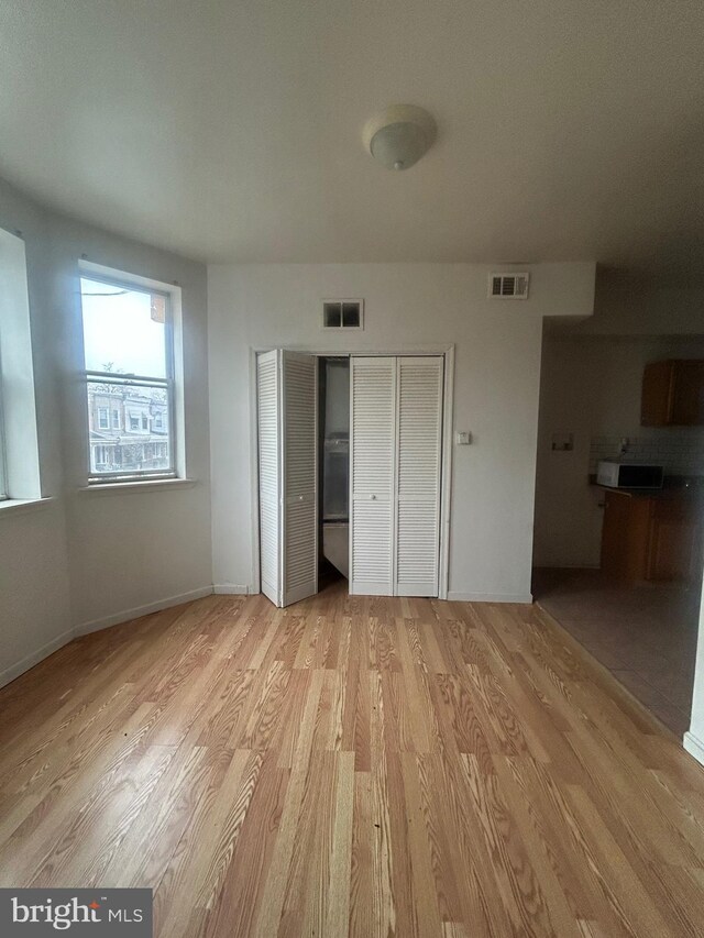 unfurnished bedroom with baseboards, wood finished floors, a closet, and visible vents