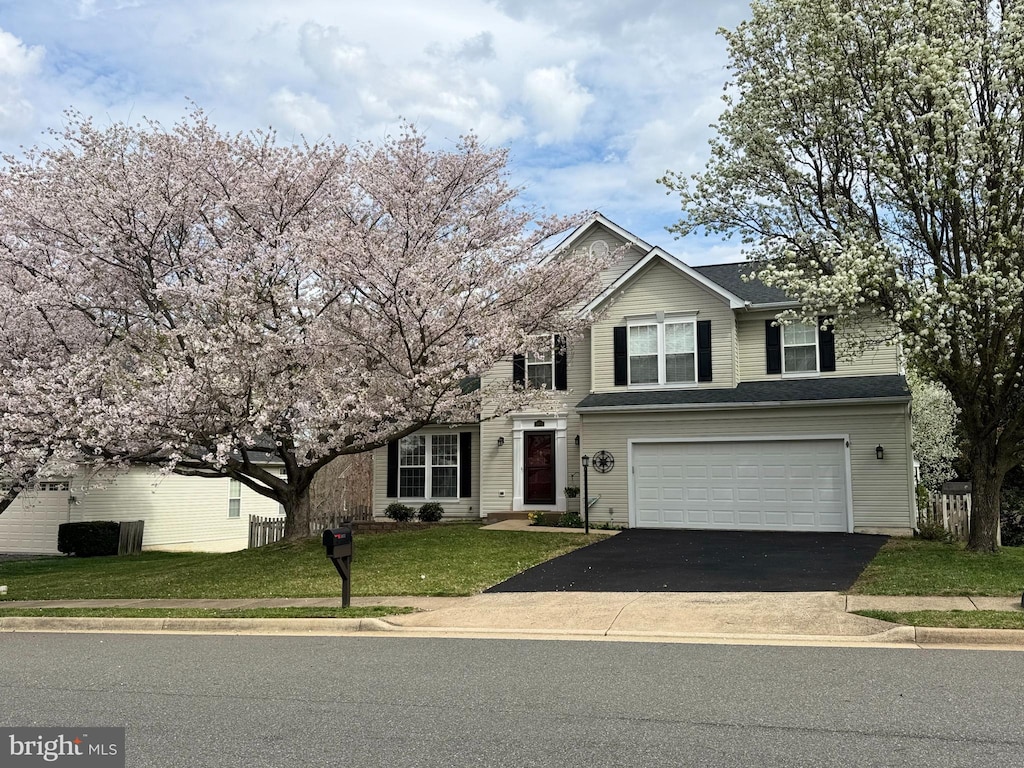traditional-style home featuring an attached garage, driveway, and a front lawn