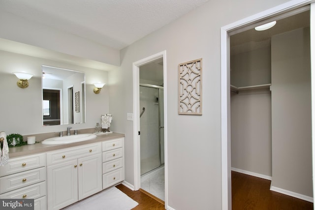 full bath featuring vanity, baseboards, a stall shower, and wood finished floors