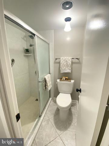 full bath with tile patterned floors, a stall shower, and toilet