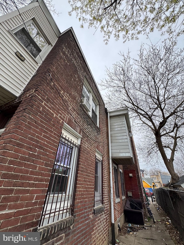 view of side of home with fence and brick siding