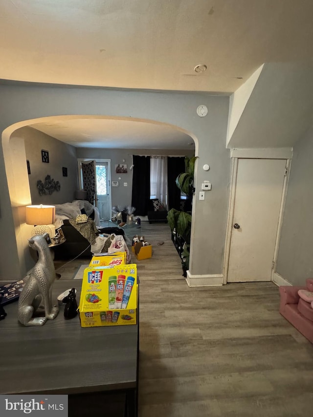 interior space featuring arched walkways, baseboards, and wood finished floors