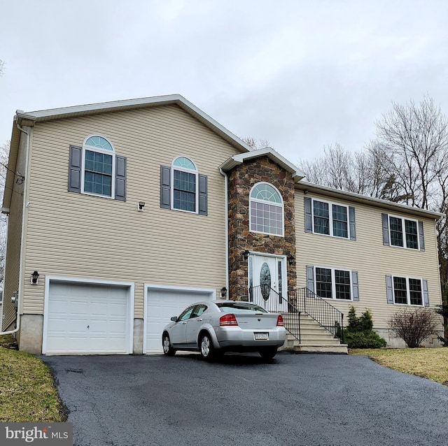 view of front of home featuring a garage, aphalt driveway, and stone siding