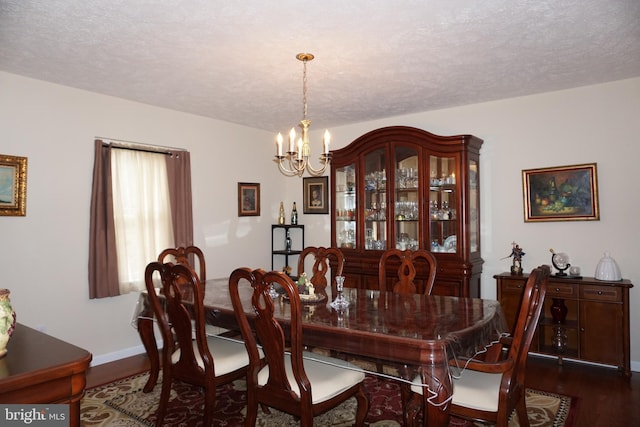 dining space featuring baseboards, a textured ceiling, an inviting chandelier, and dark wood finished floors