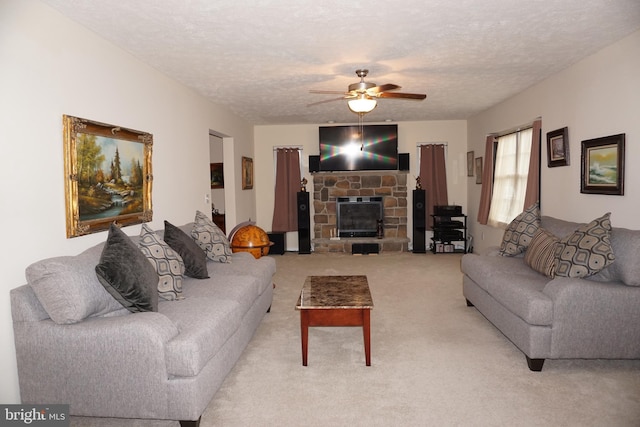 living room with a textured ceiling, light carpet, a fireplace, and a ceiling fan