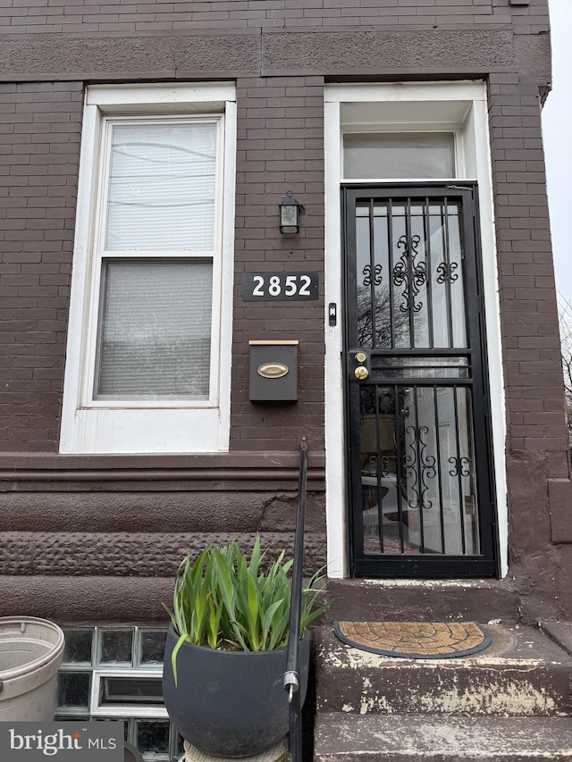 doorway to property with brick siding