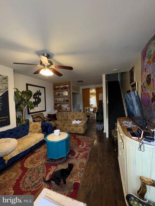 living room with stairs, a ceiling fan, and dark wood-type flooring