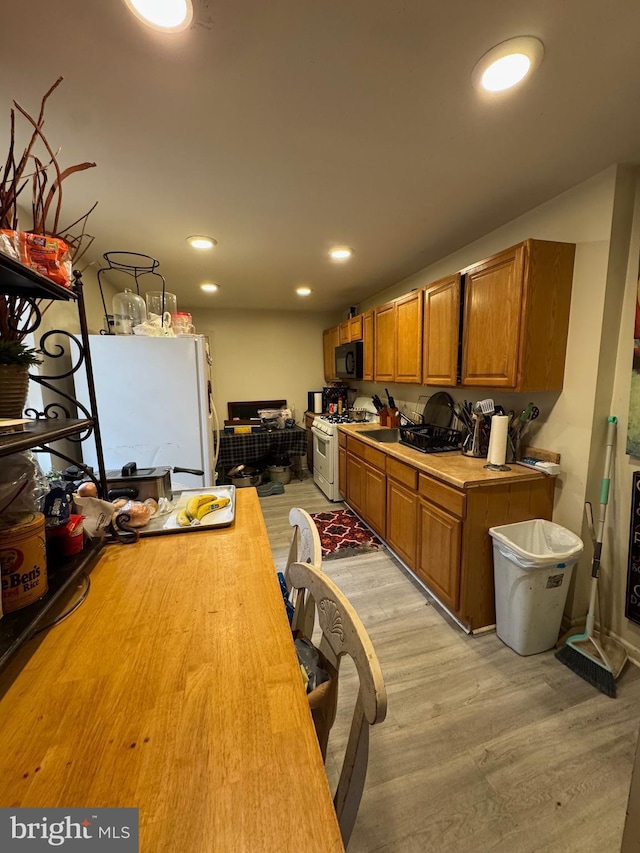 kitchen featuring white appliances, brown cabinets, butcher block countertops, and light wood-style floors